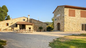 A stone building with a gravel driveway, outdoor seating, and a small garden area. - Villa San Cresci by MMega (Vicchio)