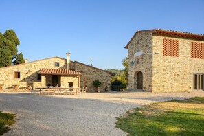 A stone building with a gravel driveway, outdoor seating, and a small garden area.