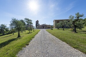 Un chemin de gravier mène à un bâtiment en pierre, sous un ciel dégagé.