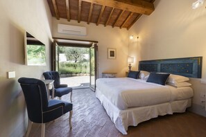Een slaapkamer met een bed, een stoel, een tafel en uitzicht op de omgeving.