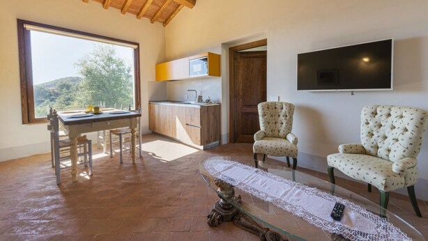 A spacious room with a dining table, two chairs, a TV mounted on the wall, and a view of the outdoors. - Villa San Cresci by MMega (Vicchio)