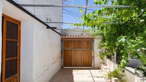 Ein schmaler, gefliester Gang mit einer Holztür am Ende, begrenzt von weißen Wänden und einem sichtbaren Metalldachaufbau.