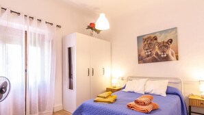 Ein Schlafzimmer mit einem Bett, einem Kleiderschrank, einem Schreibtisch und einem Gemälde von Löwen.