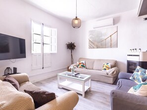 A modern living room with a flat-screen TV, a sofa set, a coffee table, and a fireplace.