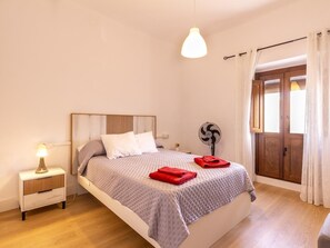 A bedroom with a bed, bedside table, lamp, fan, and a view of the outside. - Fantastic rural house in the Lecrín Valley (Lecrín (Talará))