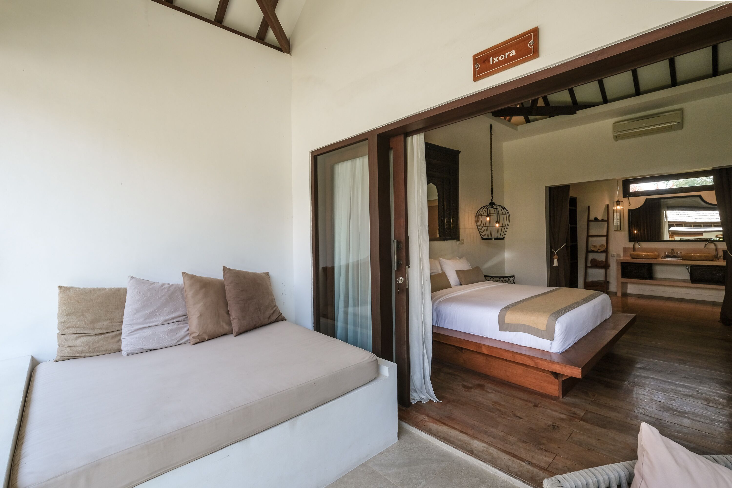 A bedroom with a bed, a sofa, and a wooden floor.