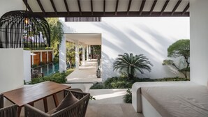A bedroom with a view of a pool and outdoor seating area. - Aram Residence (Canggu)