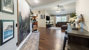 A spacious living area with a wooden floor, a dark brown sofa, a coffee table, and a ceiling fan. - Yosemite, Hot Tub, Pets - Memories! (Oakhurst)