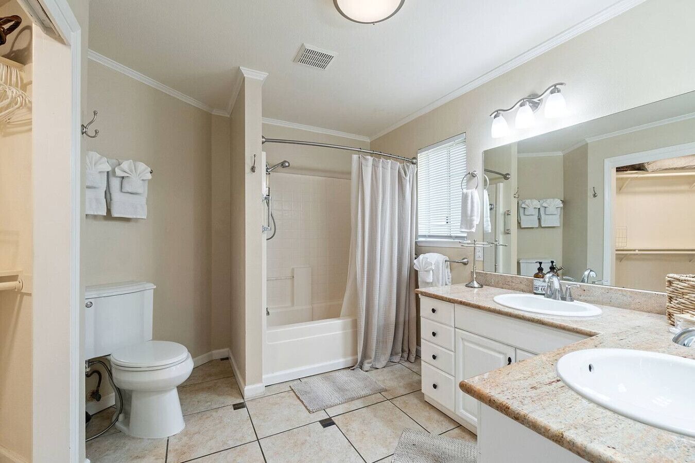 Un baño con inodoro, ducha y dos lavamanos.