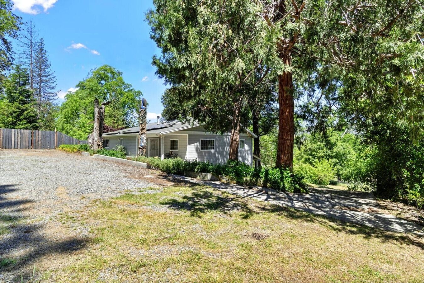 A single-story house with a gravel driveway and a wooden fence.