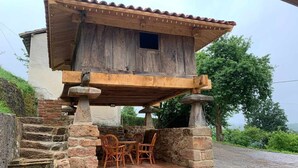 Une structure rustique en bois, dotée d’un escalier en pierre menant à un patio couvert aménagé avec des meubles en osier.