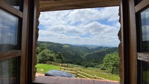 Une fenêtre donnant sur une vallée verdoyante et des collines lointaines.