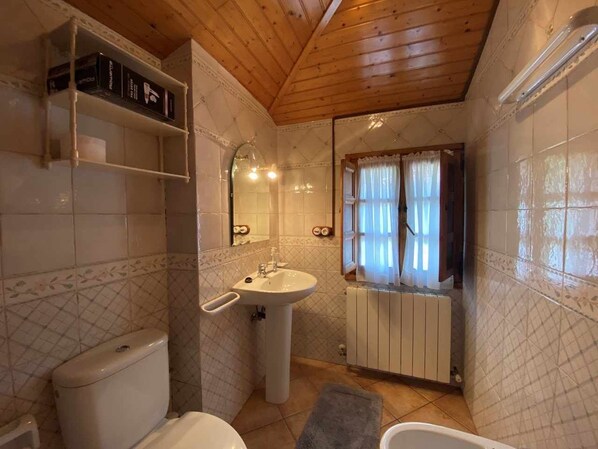 A compact bathroom with a toilet, sink, and window. - Kiko Rural Cottage, Asturias CA-AS-4727 (Fadiello)