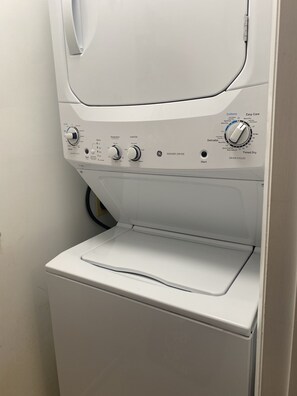 A front view of a white washer and dryer unit with control knobs for temperature, load size, and cycle selection.