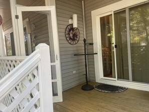 En træterrasse med hvid gelænder, en dør der fører ind til et rum, og en dekorativ vægdekoration.