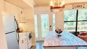 Una cocina con piso de madera, una isla central y una lámpara colgante.