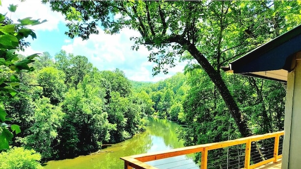 Una terraza de madera con vistas a un río rodeado de abundante vegetación.