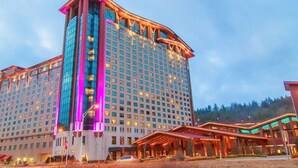 Un gran hotel con varios pisos, una torre central destacada y un área de entrada cubierta.
