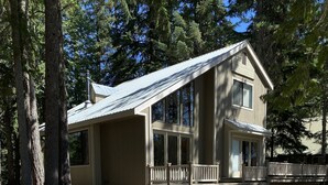 A two-story house with a porch, a fire pit, and a deck.