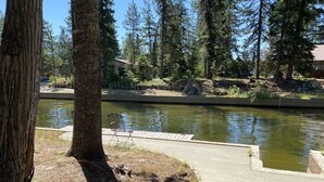 A serene lakeside view with a wooden dock and a metal chair.