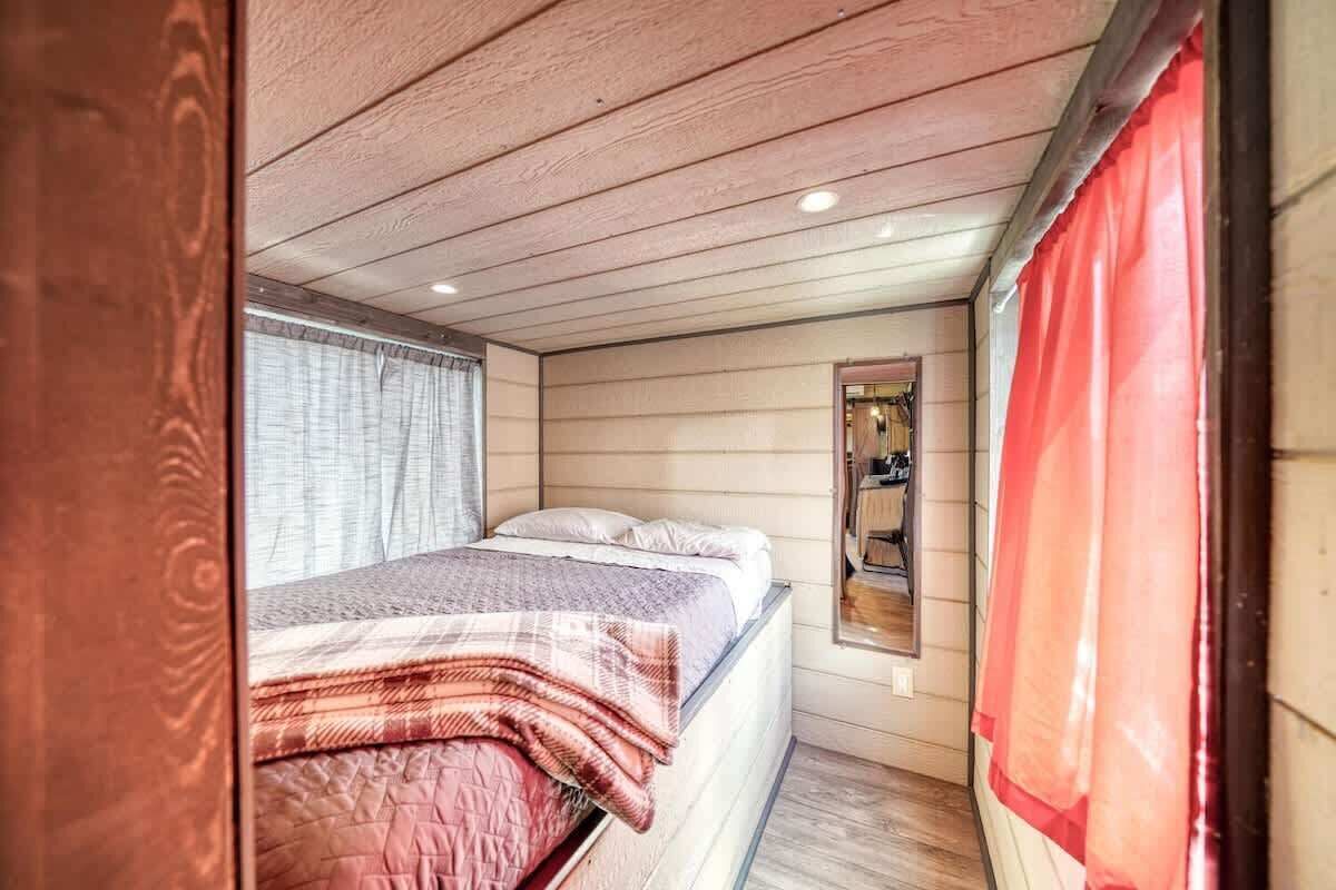 Ein gemütliches Schlafzimmer mit Bett, einem Fenster mit Vorhängen und einem Spiegel an der Wand.