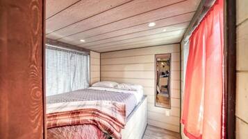 Ein gemütliches Schlafzimmer mit Bett, einem Fenster mit Vorhängen und einem Spiegel an der Wand.