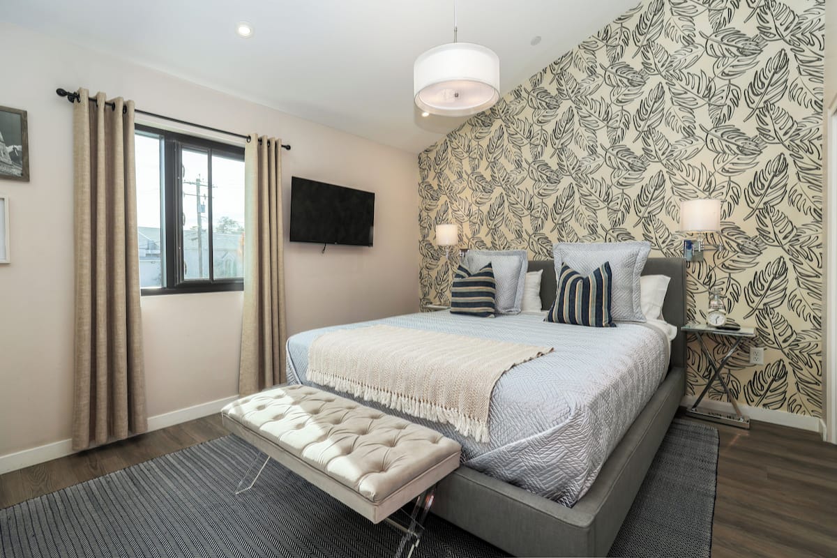 A bedroom with a bed, a TV, a bedside table, and a window with curtains.