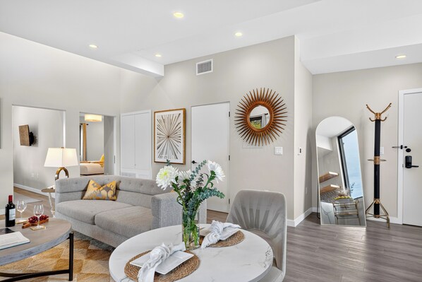 A modern living room with a grey sofa, a round coffee table, and a mirror. - The Lofts at The Market by AvantStay (Paso Robles)