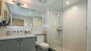 A modern bathroom with a glass-enclosed shower, a toilet, and a sink with a mirror above it.
