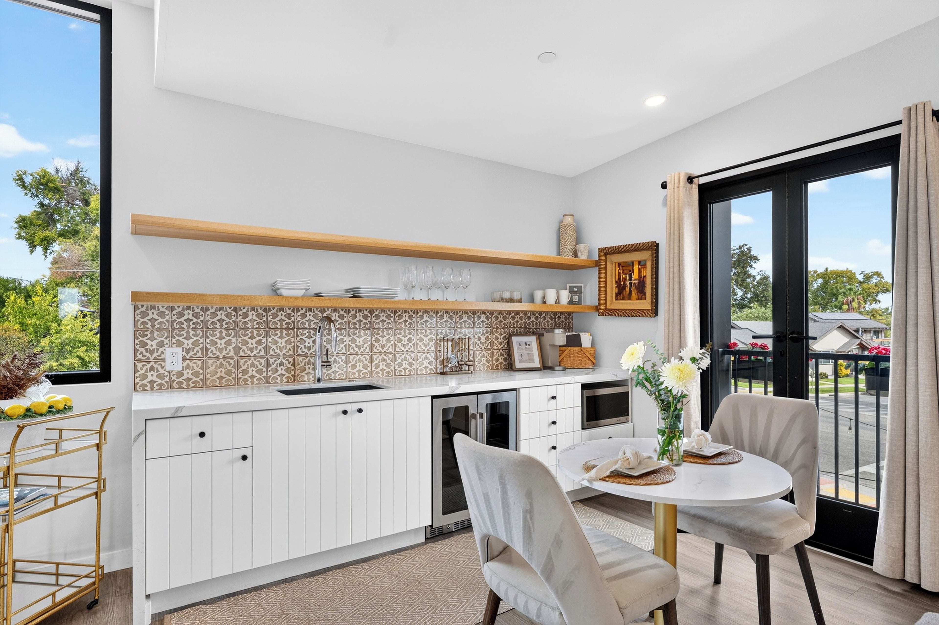 A modern kitchen with white cabinets, a built-in oven, and a dining area with a round table and chairs.