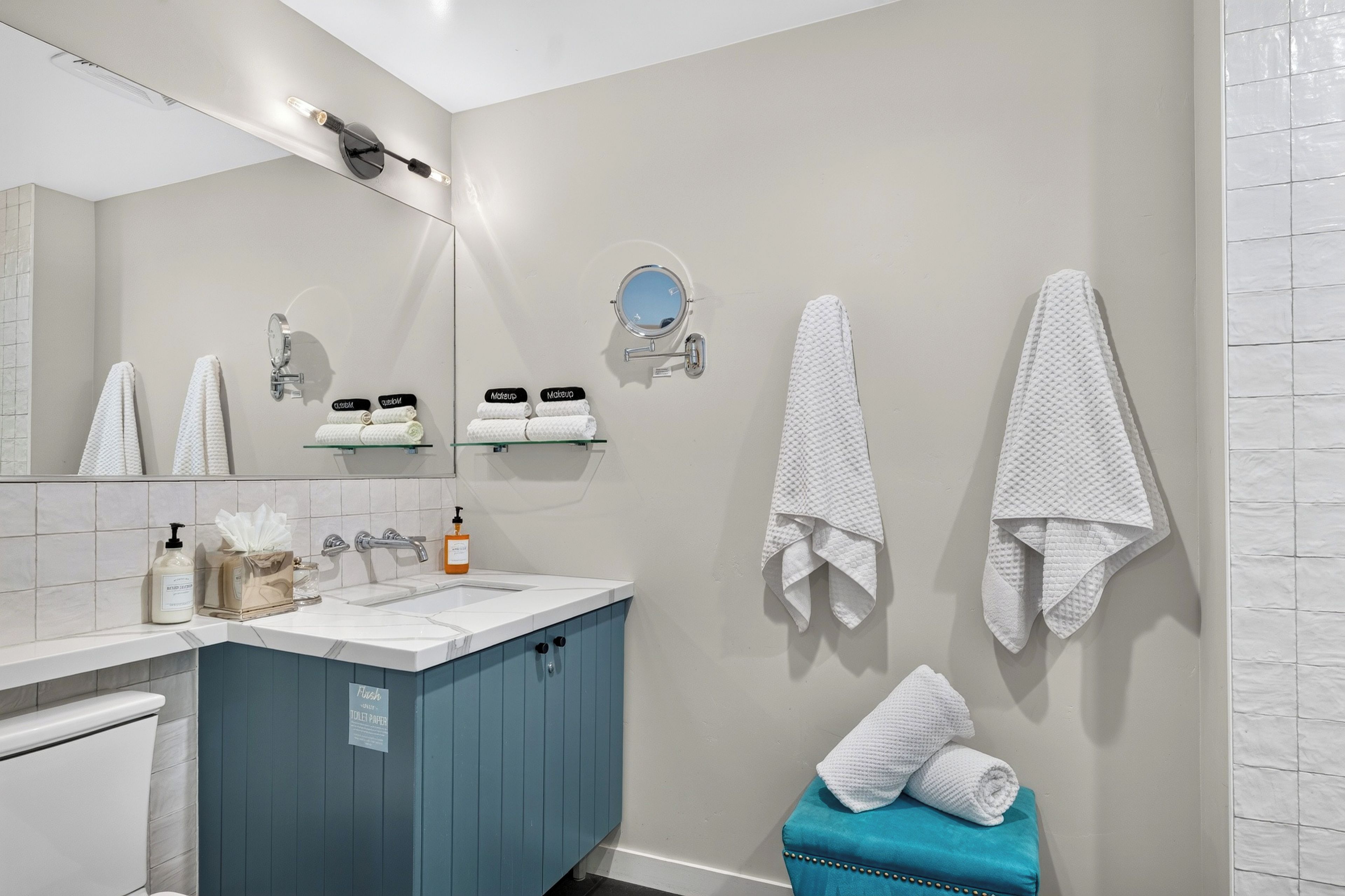 Un baño con un lavabo blanco, un espejo, un perchero para toallas y un armario azul.