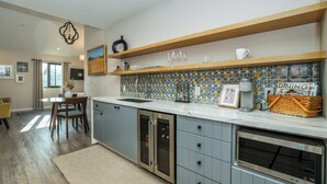 A modern kitchen with a built-in oven, a dining area with a table and chairs, and a patterned rug on the floor.