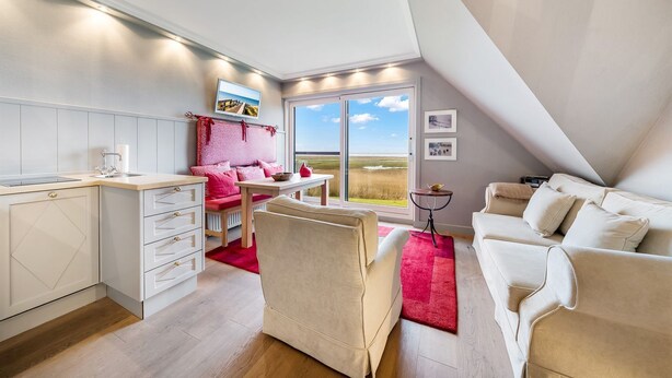 Een moderne loft slaapkamer met een groot raam, een gezellige zithoek en een kitchenette.