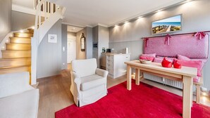 Een moderne woonkamer met een trap, een eethoek en uitzicht op zee door een groot raam.