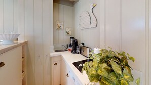 Cocina compacta con lavamanos, cafetera, tostadora y un adorno en la pared.