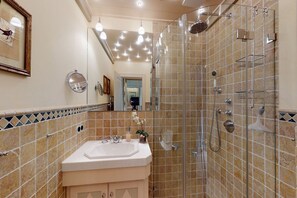 A bathroom with a sink, mirror, and shower.