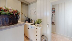 Una cocina con armarios blancos, una cafetera, un tostador y una planta en maceta.