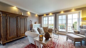 Een ruime woonkamer met een grote houten kast, een bank, een salontafel en uitzicht door grote ramen.