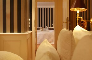 A hotel room with a bed, a bedside lamp, and a view of a striped wall and another room. - Strandhafer - Wohnung in Absolut Ruhiger Lage an den Salzwiesen Unweit des Morsumer Kliffs (Sylt-Ost)
