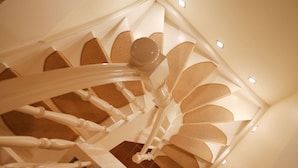 En spiraltrappe med et moderne design, karakteriseret ved en central søjle og brede trin med en struktureret overflade.