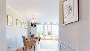 A dining area with a chandelier, framed artwork, and a view to the outdoors.