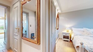 A bedroom with a bed, a nightstand, a lamp, and a large mirror.
