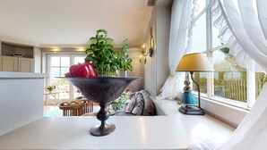 A kitchen with a large decorative bowl on the counter, a potted plant, and a window with curtains. - Pure Sylt - Exclusive luxury apartment in a quiet location on the Munkmarsch Wadden Sea. (Sylt)