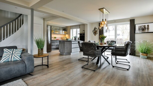 Una cocina moderna con armarios grises, una isla central y un comedor con sillas de mimbre y una mesa de madera.