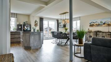 Een ruime woonkamer met keuken, eettafel en zithoek.