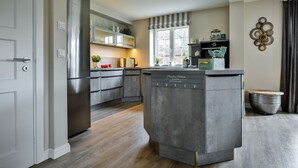 Una cocina moderna con armarios grises, lavavajillas integrado y una ventana con cortinas a rayas.