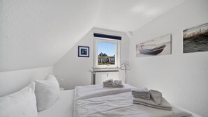 Un dormitorio con cama, radiador, ventana con vistas y un cuadro en la pared.