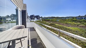 Un balcón con vistas a casas costeras, una terraza de madera y una barandilla.