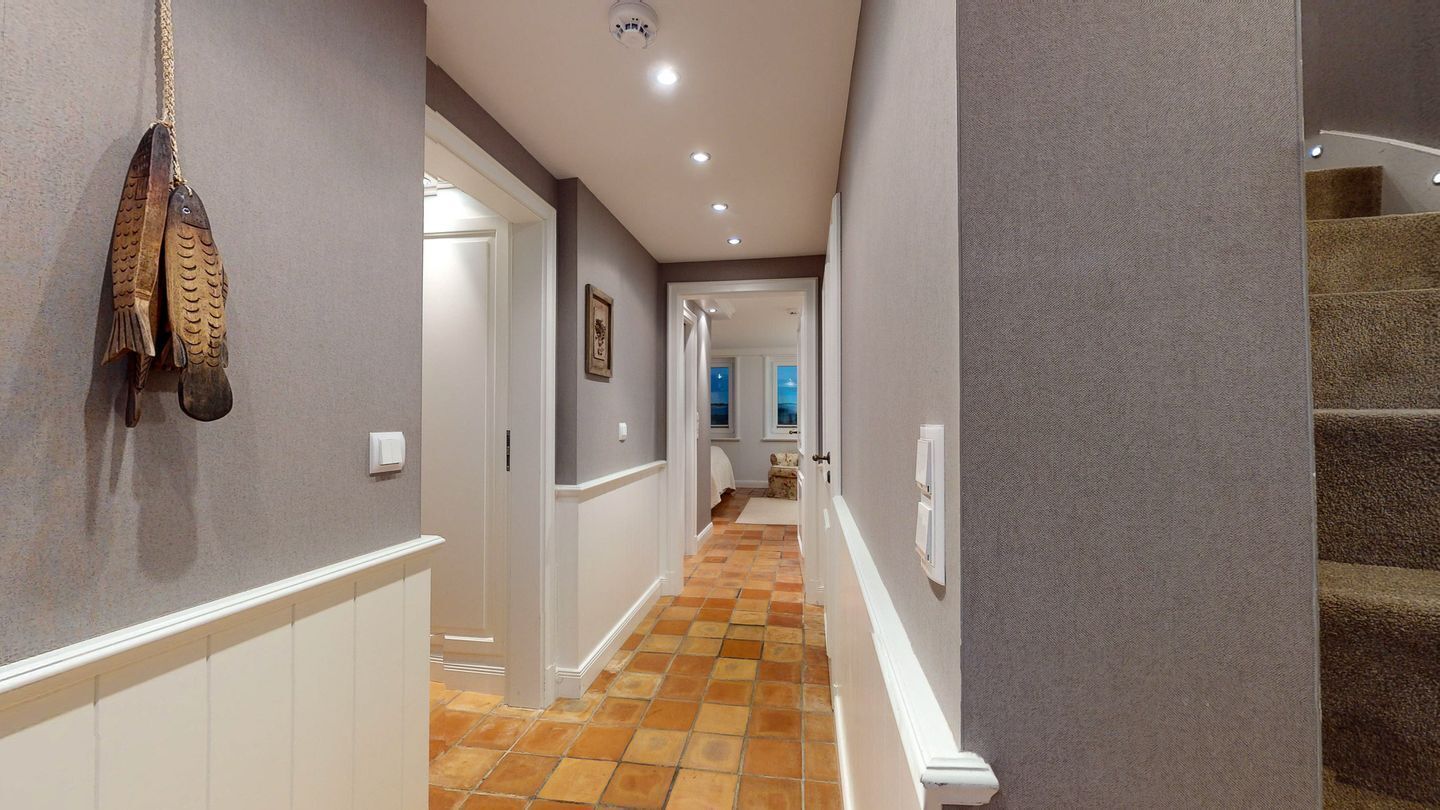 A hallway with a tiled floor, a wooden fish decoration, and a staircase.