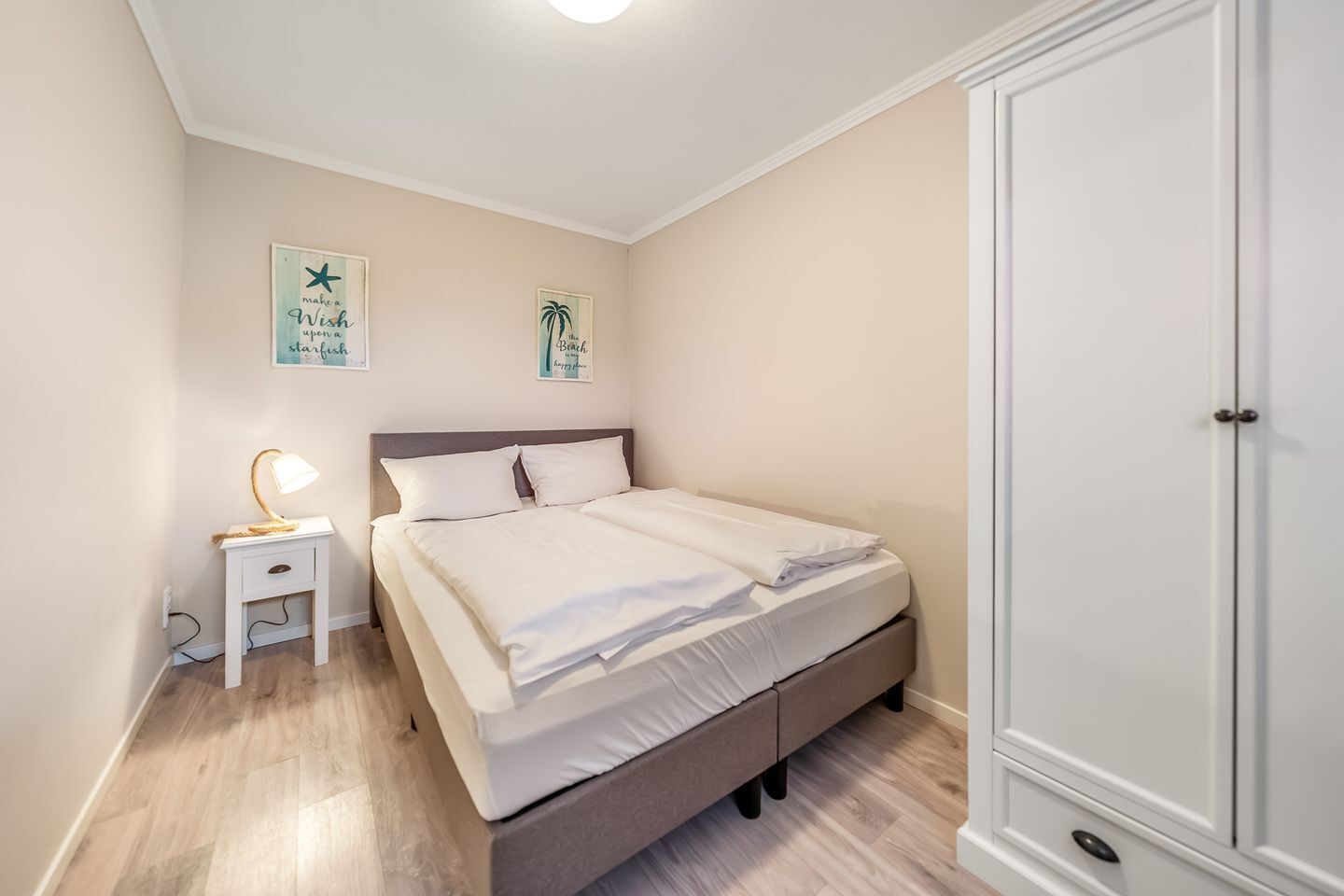 Une chambre à coucher avec un lit, une table de chevet, une lampe et une armoire.